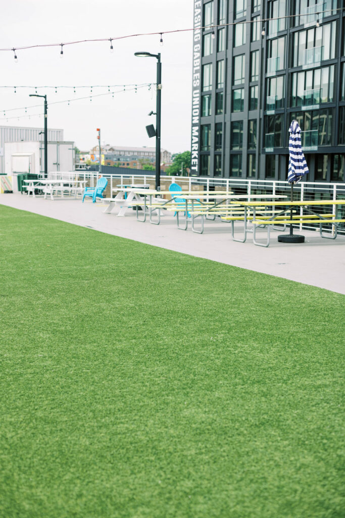Artificial turf lawn area on the rooftop at Union Market with picnic tables, ideal for welcome parties, mitzvahs, and wedding events.