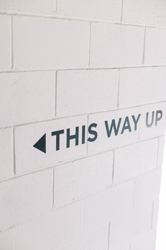 Directional mural that reads 'This Way Up' on a white brick wall at Union Market