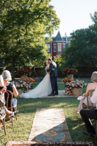 Bride and groom share their first kiss during an outdoor wedding ceremony at The Branch Museum in Richmond, Virginia.