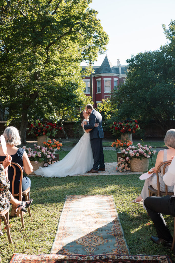 Bride and groom share their first kiss during an outdoor wedding ceremony at The Branch Museum in Richmond, Virginia.