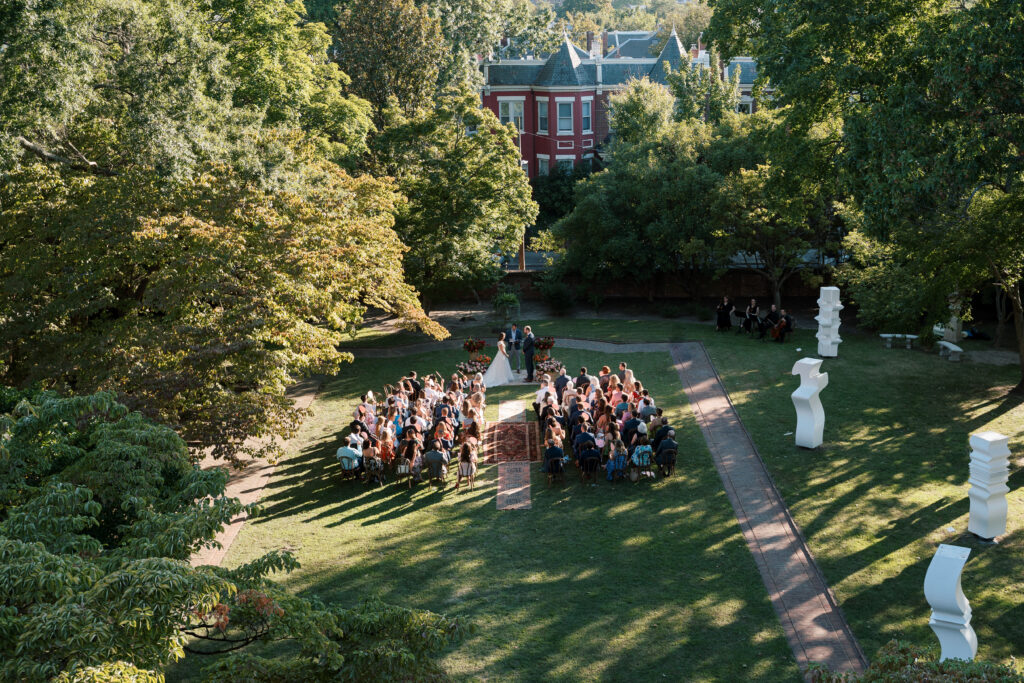 Aerial view of outdoor wedding ceremony at The Branch Museum in Richmond, Virginia, with guests seated in the garden during the wedding ceremony.
