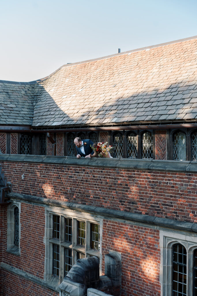 Bride and Groom peeking over historic balcony at The Branch Museum before wedding ceremony in Richmond, VA