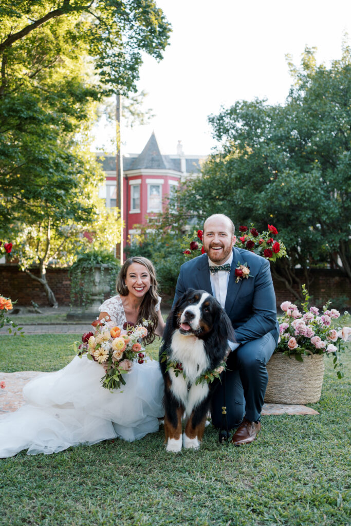 Bride and groom with their Bernese Mountain Dog wearing a floral collar during their garden wedding at The Branch Museum in Richmond, Virginia