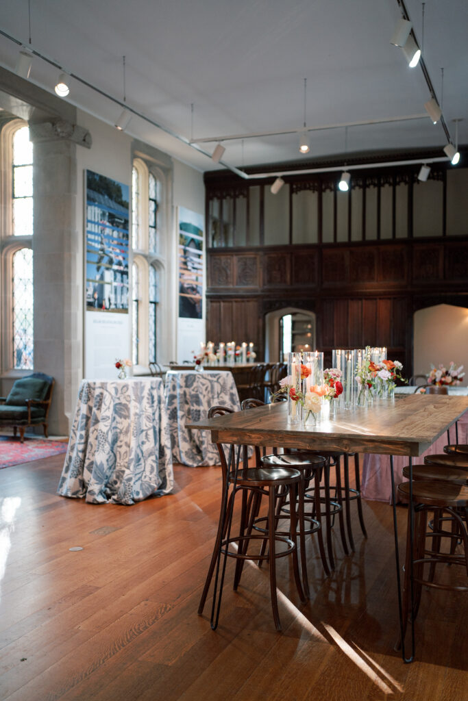 Cocktail Style Reception at The Branch Museum with botanical linen-covered high-top tables and vintage chairs against the venue’s architectural exhibit panels. Richmond Wedding Venue. 