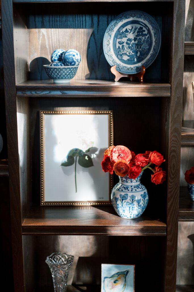 Close-up of red ranunculus in a chinoiserie vase with pressed floral artwork on display at The Branch Museum wedding.