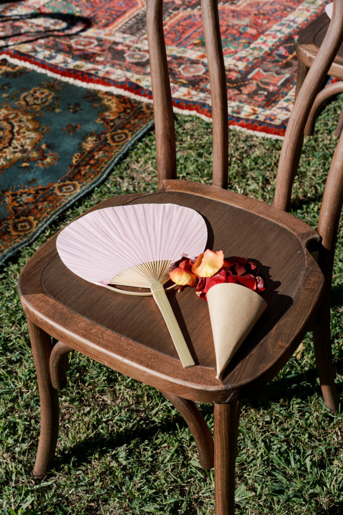 Paper fan and petal cone on wooden ceremony chair at The Branch Museum garden wedding in Richmond, Virginia