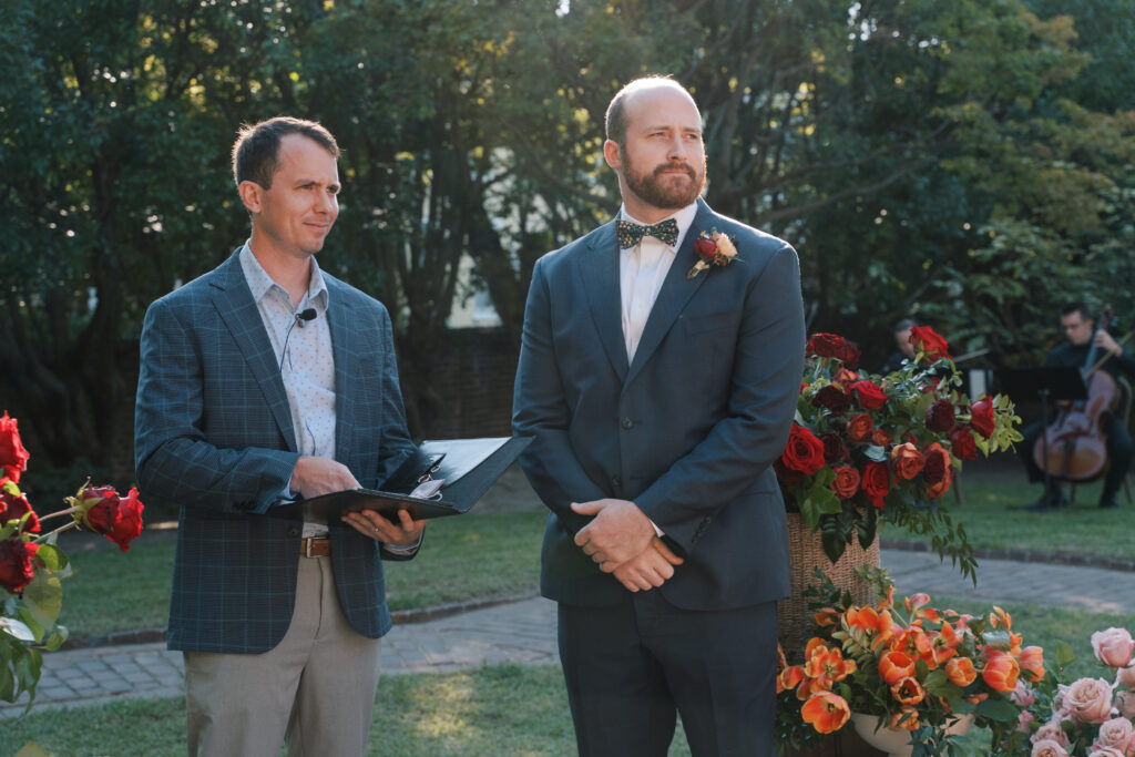 Groom and officiant await the ceremony start at The Branch Museum, a Richmond wedding venue known for its romantic garden ceremonies. Richmond Wedding Planner.