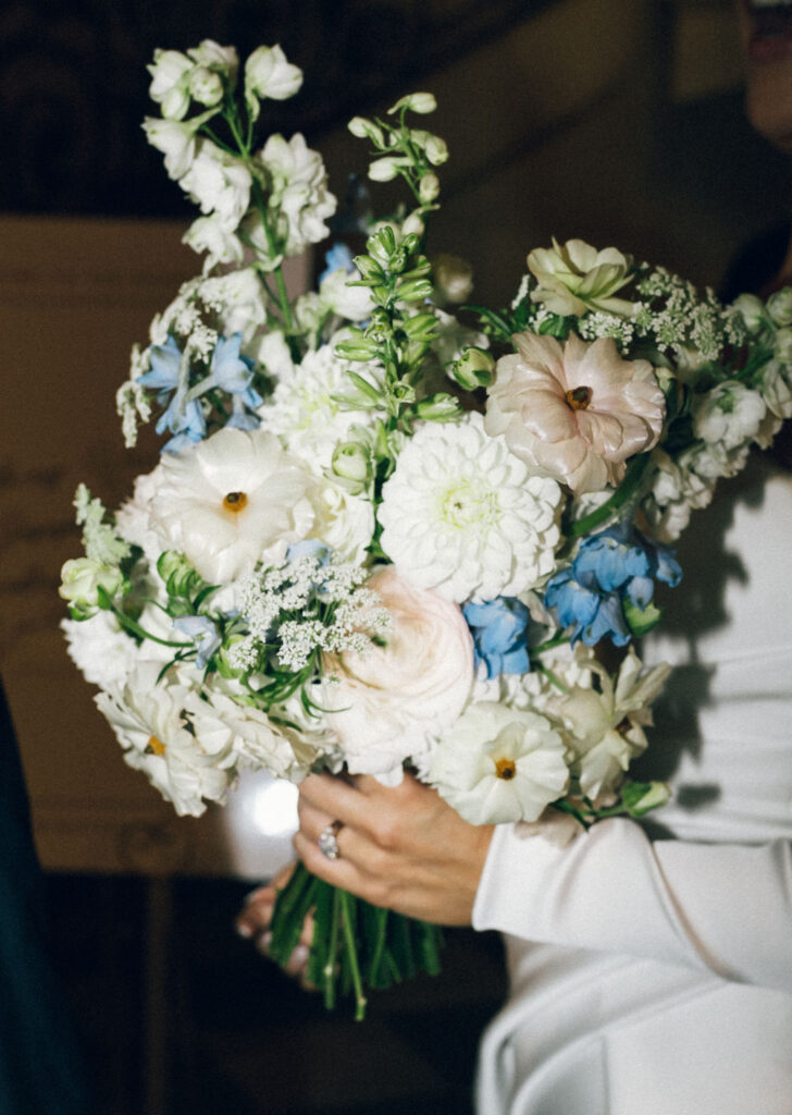 Close-up of bride’s bouquet with white lisianthus, blush ranunculus, and soft blue delphinium for a classic Meridian House wedding.