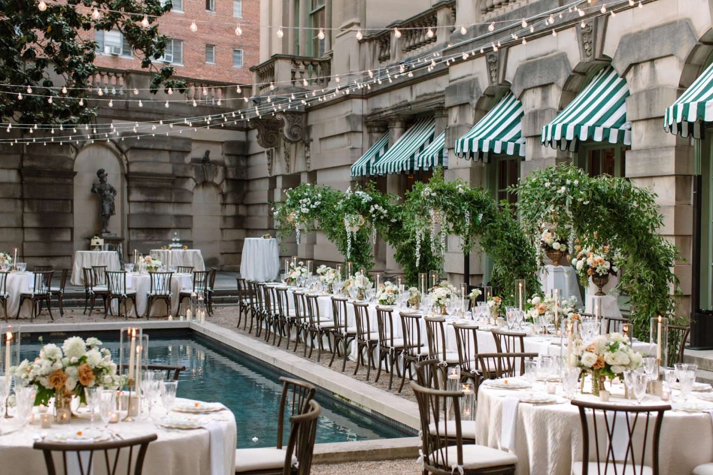 The garden of Anderson House set up for a wedding reception, with long and round tables surrounding a square reflecting pool