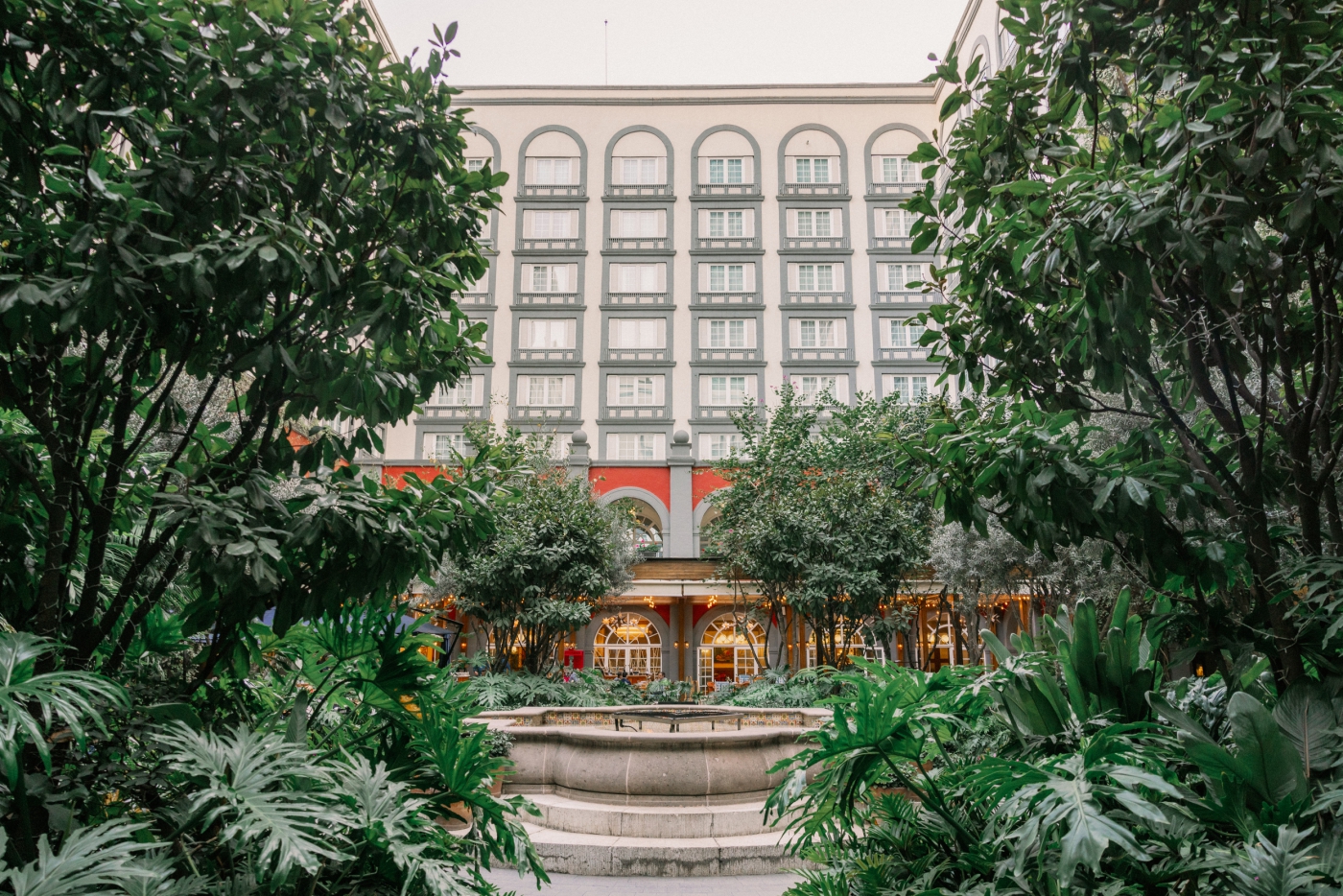 A view of Four Seasons CDMX with large green tropical plants and a fountain in the center