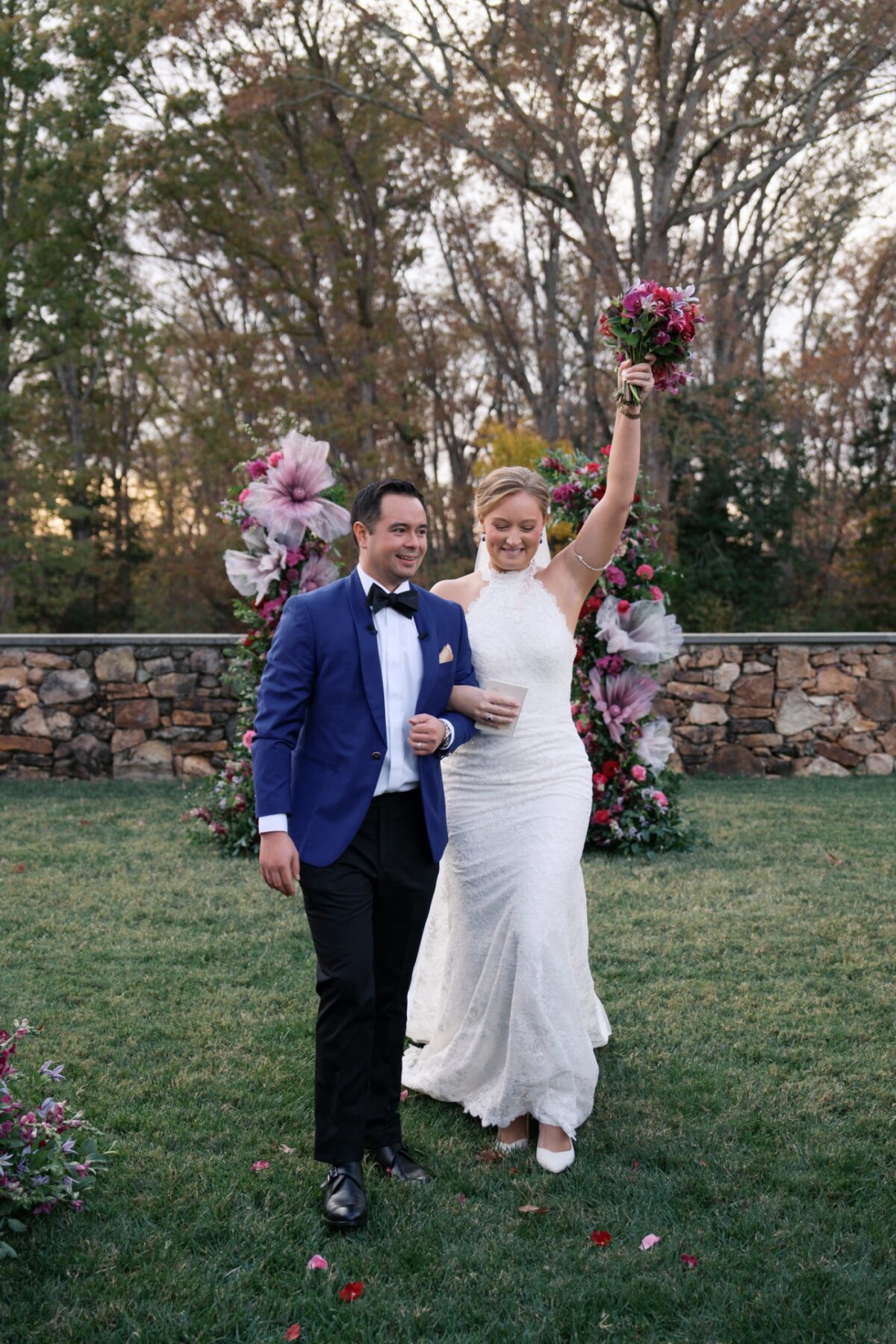 A bride raises her bouquet as she and the groom walk back up the aisle