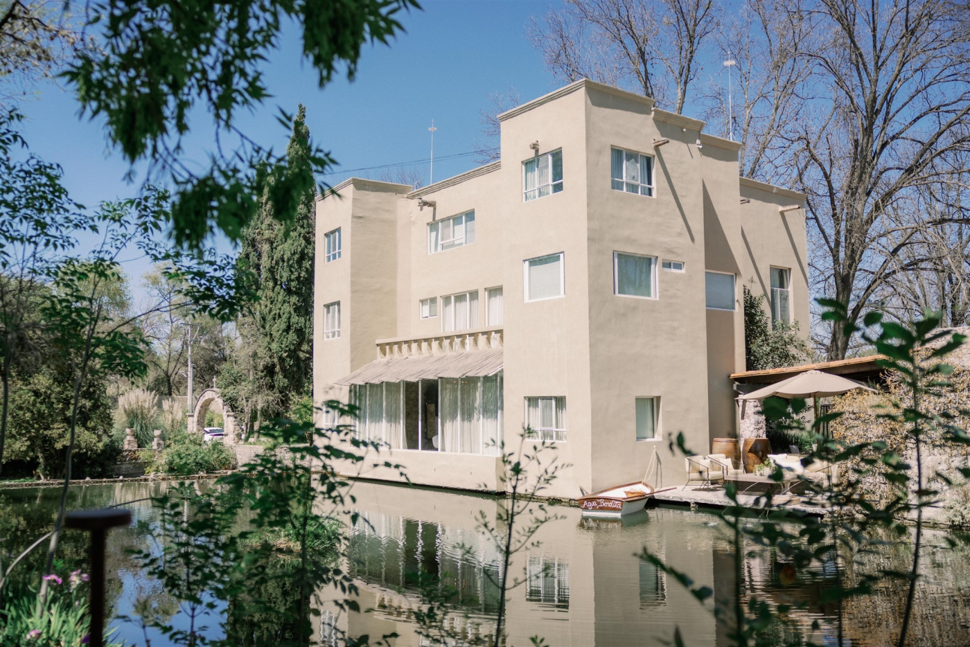 A cream-colored, three-story villa on the shores of a lake in San Miguel